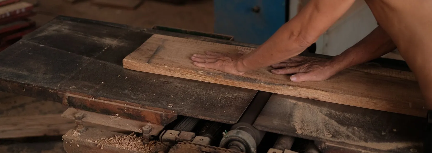 Pengrajin menyerut papan jati di workshop furniture